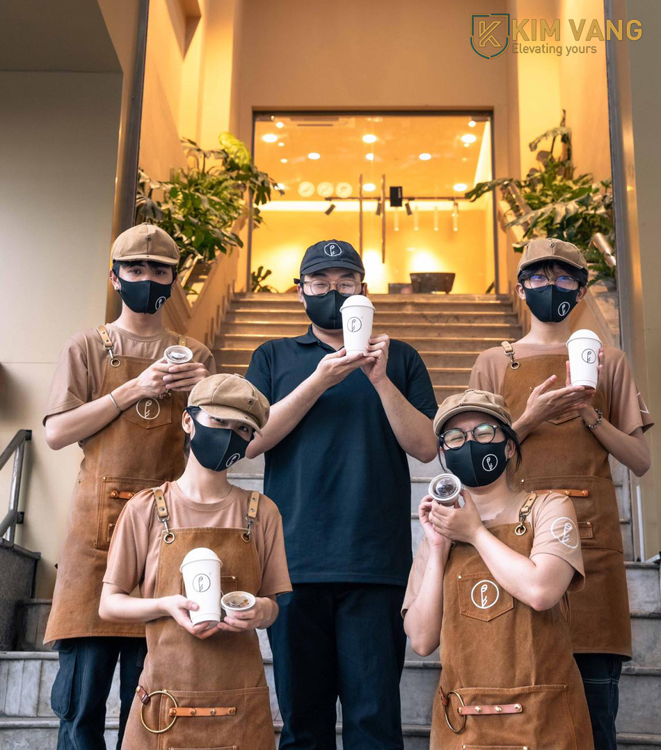 Tạp dề màu trung tính giúp bộ đồng phục quán cafe nhìn chuyên nghiệp hơn mà không cần thiết kế phức tạp.
